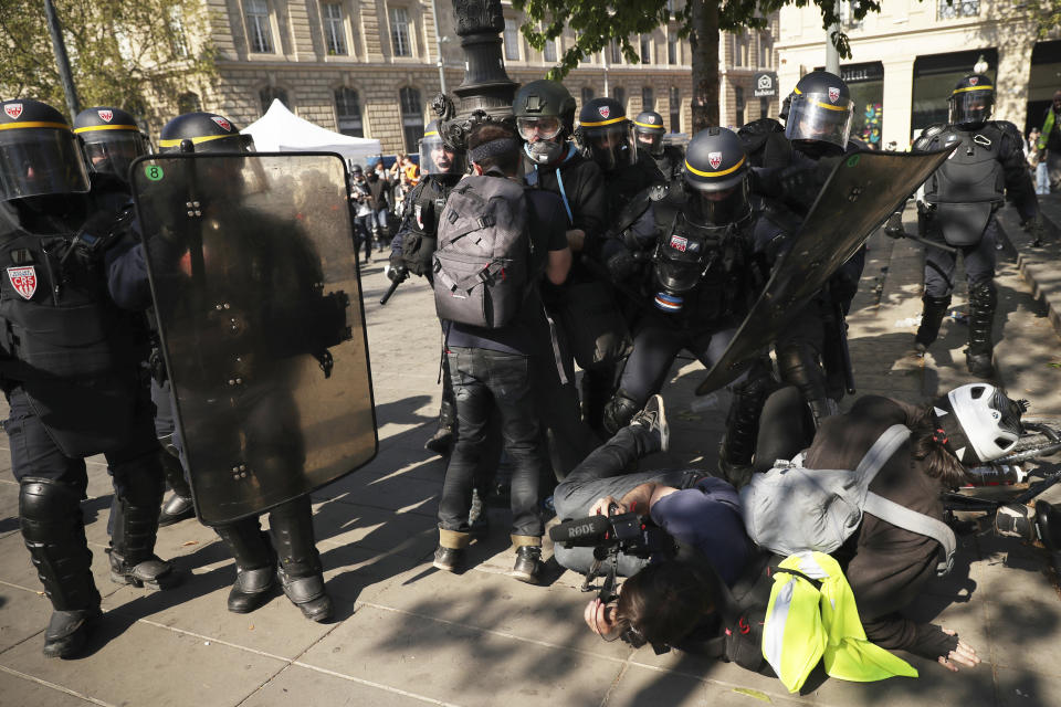 Police confront protestors and a photographer during a yellow vest demonstration in Paris, Saturday, April 20, 2019. French yellow vest protesters are marching anew to remind the government that rebuilding the fire-ravaged Notre Dame Cathedral isn't the only problem the nation needs to solve. (AP Photo/Francisco Seco)