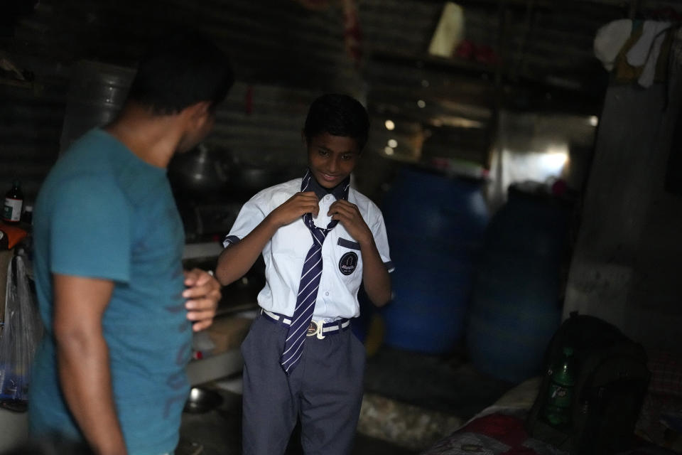 Raju, right, talks with his father Jaidul Islam after coming back from school at their home in a poor neighborhood in Bengaluru, India, Tuesday, July 19, 2022. A flood in 2019 in the Darrang district of India's Assam state started Raju, his sister Jerifa and their parents that led the family from their Himalayan village to the poor neighborhood. (AP Photo/Aijaz Rahi)