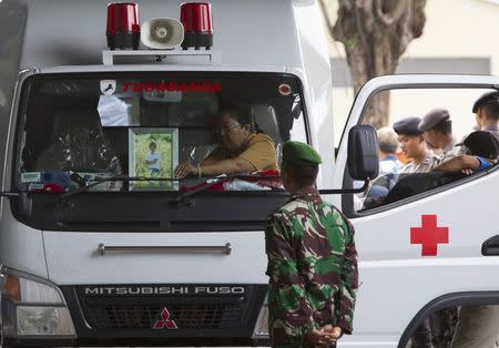 A family member of AirAsia QZ8501 passenger Jou Brian Yolnito places his picture on the window of a hearse after his remains were returned to his family at Bhayangkara hospital, Surabaya January 6, 2015. REUTERS/Sigit Pamungkas