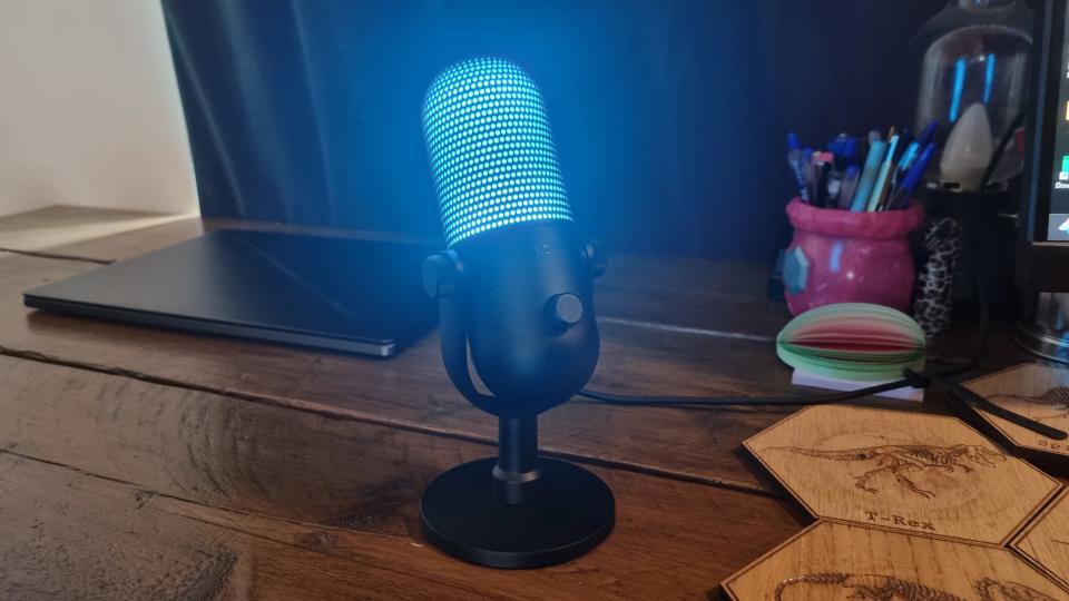 The Razer Seiren V3 Chroma lit up in blue, on a desk