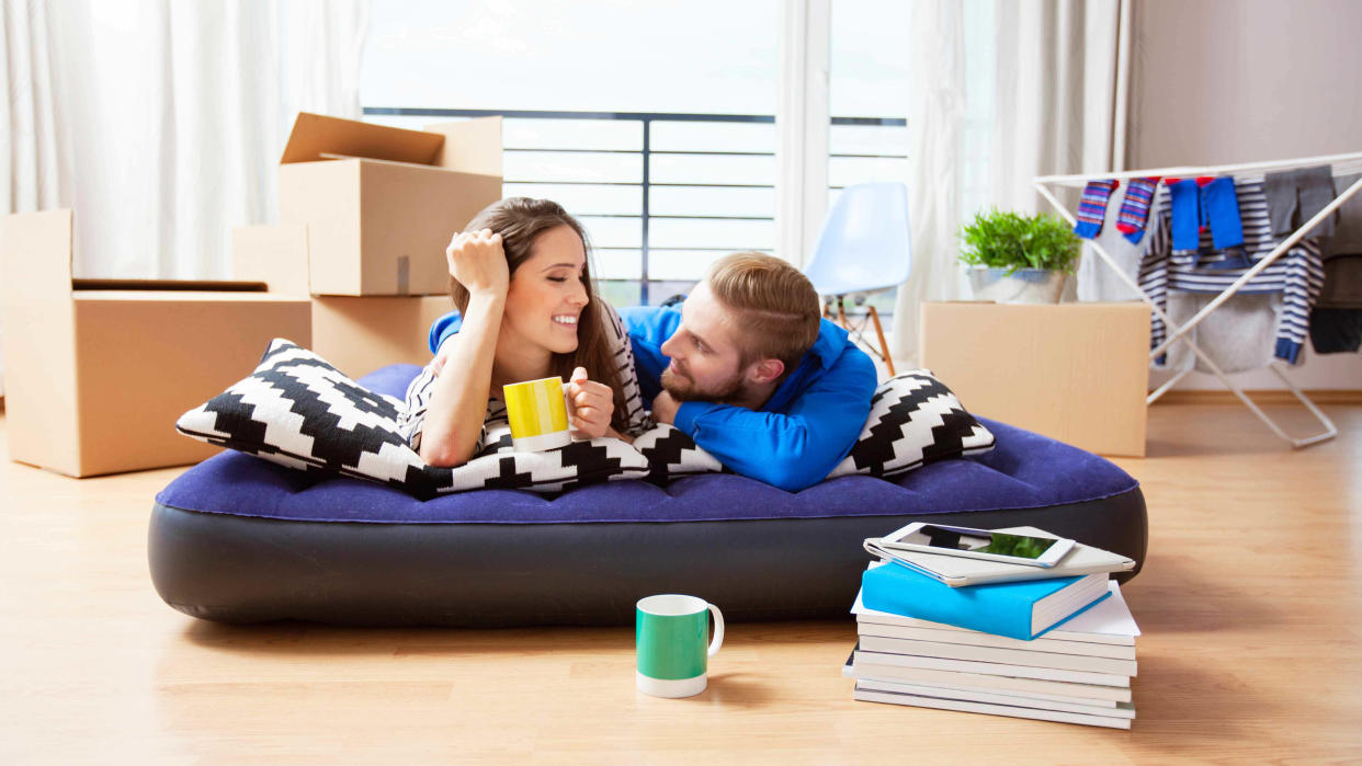  A man and a woman lie and talk on a blow up mattress in their new house. 