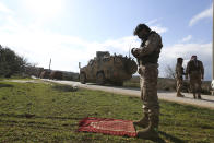 Syrian rebel fighter prays as a Turkish military convoy stops in Idlib province, Syria, Saturday, Feb. 22, 2020. A Turkish soldier was killed in Syria's northwest Idlib province, state-run Anadolu news agency reported Saturday. (AP Photo/Ghaith Alsayed)