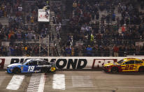 Martin Truex Jr. (19) crosses the finish line in front of Joey Logano (22) to win the NASCAR Cup Series auto race at Richmond Raceway in Richmond, Va., Saturday, April 13, 2019. (AP Photo/Steve Helber)