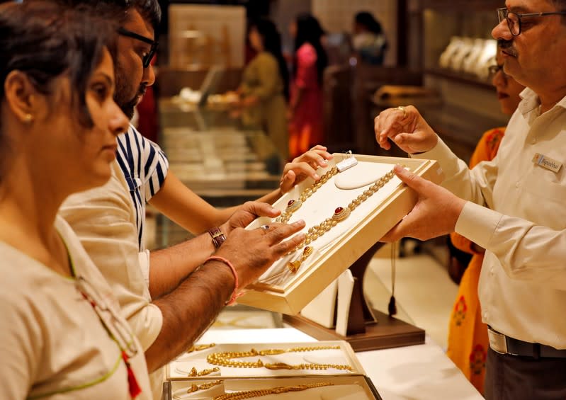 A salesman shows a gold necklace to customers at a jewellery showroom in Ahmedabad