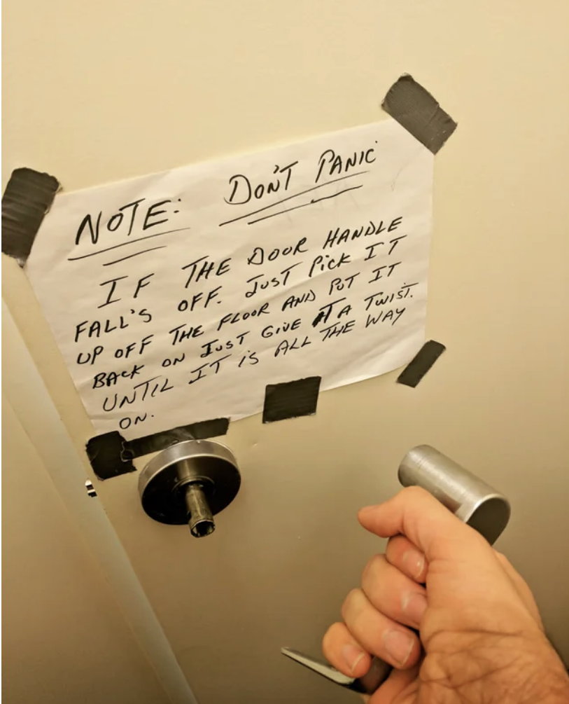 A sign on a door tells people not to panic if the handle comes off in their hand and gives instructions about how to put it back on