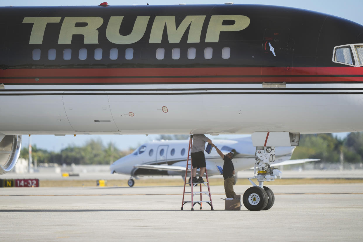 Maintenance personnel are seen working on the personal airplane of former President Donald Trump at Palm Beach International Airport in West Palm Beach, Fla., Wednesday, March 22, 2023. (AP Photo/Gerald Herbert)