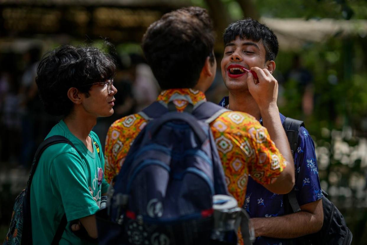 A participant applies lipstick on another during an event that celebrates the Pride month and the LGBTQ community in New Delhi, India in June 2022. A queer international student studying in Canada says he has to hide his true identity when he visits family in India. (Altaf Qadri/AP - image credit)