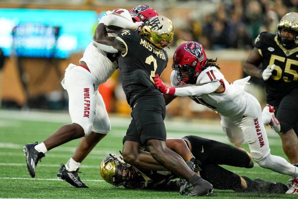 Wake Forest Demon Deacons defensive back Malik Mustapha (3) tries to hold onto North Carolina State Wolfpack running back Delbert Mimms III (34) for a tackle during the second half of their 2023 game. Jim Dedmon-USA TODAY Sports