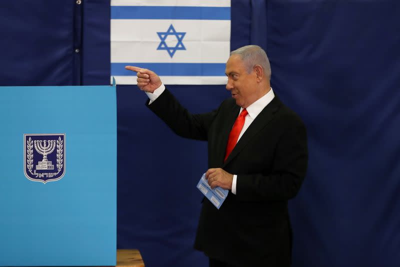 FILE PHOTO: Israeli Prime Minister Benjamin Netanyahu gestures while standing near a voting booth as he prepares to cast his ballot in Israel's general election, at a polling station in Jerusalem