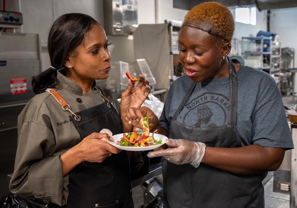 Robin Ray (left), shares lunch with Afi Aboflan in the The Food Hub kitchen in St. Louis, Mo. Ray dubbed the spontaneously-created chicken dish with peppers, onions, broccoli and sweet chili sauce “Leslie’s Magic,” after one of the kitchen’s employees.