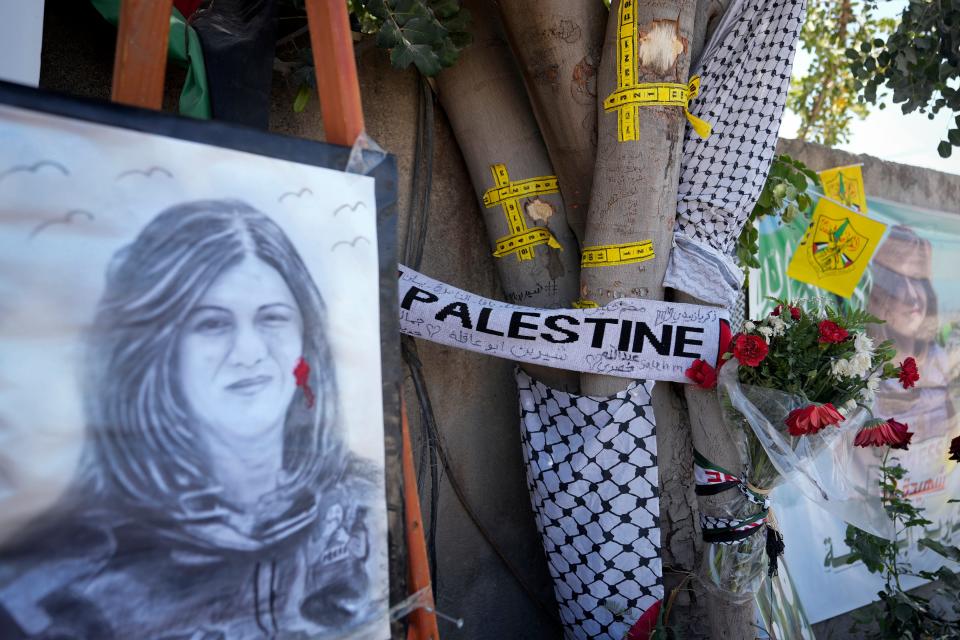 Yellow tape marks bullet holes on a tree at a makeshift memorial where Palestinian American  journalist Shireen Abu Akleh was fatally shot in the West Bank city of Jenin.