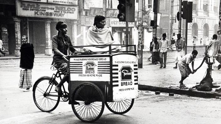 A man rides a bicycle through the streets of Calcutta in the 1980s