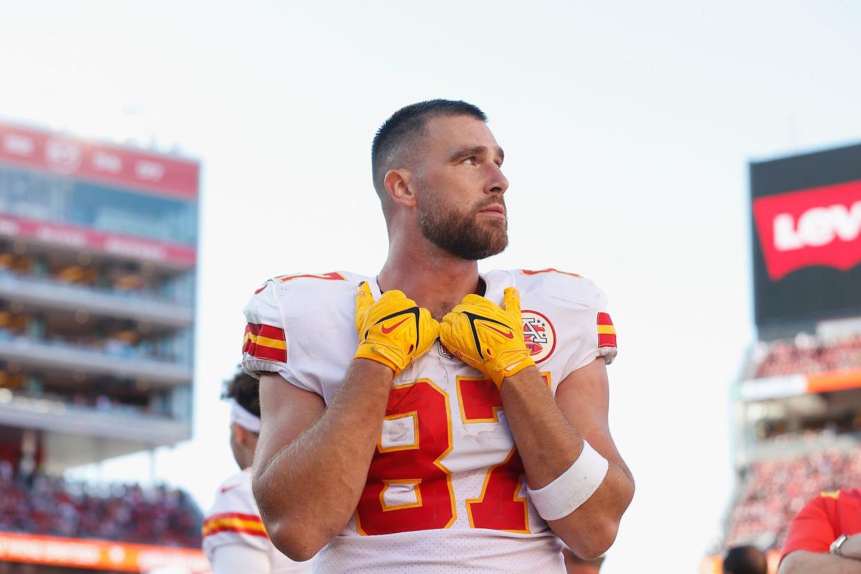 Travis Kelce rests his hands on his collar while looking off to the side during a Chiefs game.