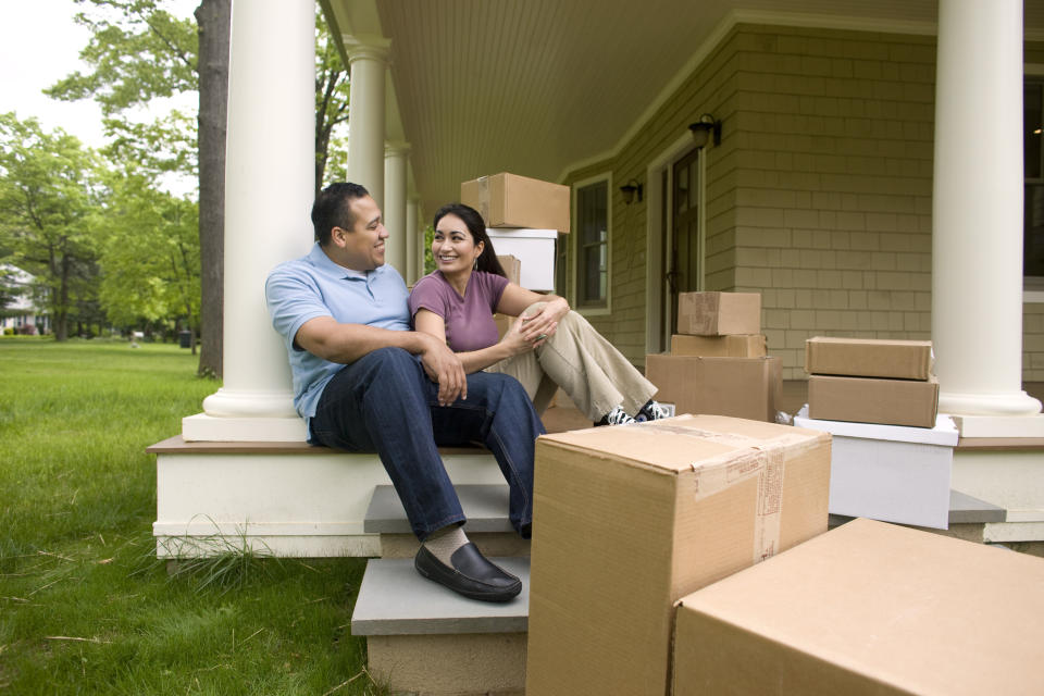 Happy couple with boxes, talking on porch