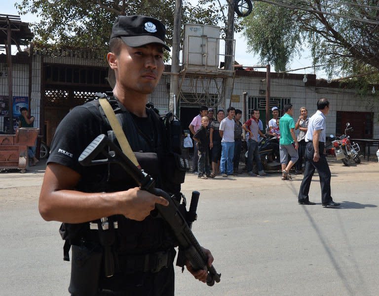 An armed Chinese policeman patrols the road leading into the riot affected town of Lukqun, Xinjiang Province, on June 27, 2013. Armed police in China's ethnically divided Xinjiang have blocked the road to the site of riots that killed 27 people a day earlier in the region's deadliest violence in years, which state media called a "terrorist incident"