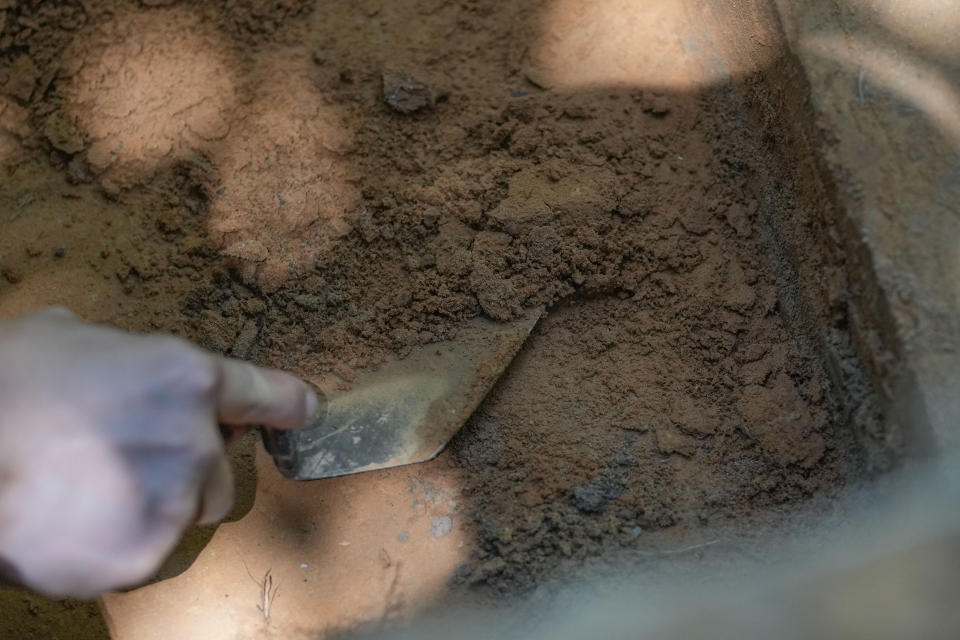 A worker digs in an archeological site in Kisatchie National Forest, La., Wednesday, June 7, 2023. This summer, archaeologists have been gingerly digging up the ground at the site in Vernon Parish to unearth and preserve the evidence of prehistoric occupation. The site was found by surveyors in 2003, according to the U.S. Forest Service. Hurricanes Laura and Delta uprooted trees and exposed some of the artifacts. Further damage has been done by looters making unauthorized digs. Forest officials say the site shows evidence of generations of people living in the area going back 12,000 years. (AP Photo/Gerald Herbert)