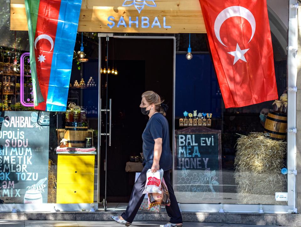 <p>Woman strolls past shop in Azerbaijani capital of Baku </p> (AFP via Getty Images)