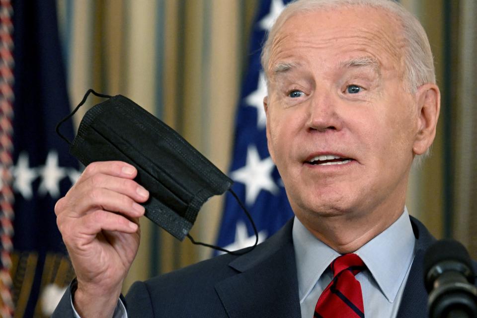 President Biden holds up a face mask while speaking in the White House.