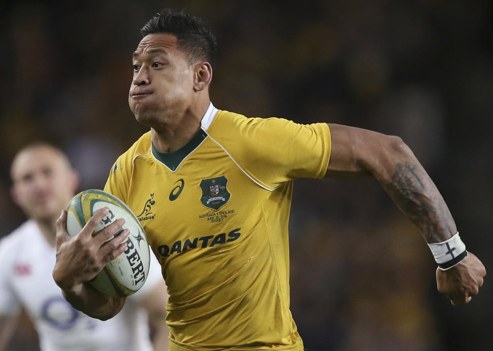 In this June 25, 2016, photo, Australian rugby union player Israel Folau, wearing tape on his wrist adorned with a cross, runs toward the try line to score against England during their rugby union test match in Sydney. Folau, one of the sport's top players, published a message on his Instagram account that said "drunks, homosexuals, adulterers, liars, fornicators, thieves, atheists, idolators. Hell awaits you." (AP Photo/Rick Rycroft)