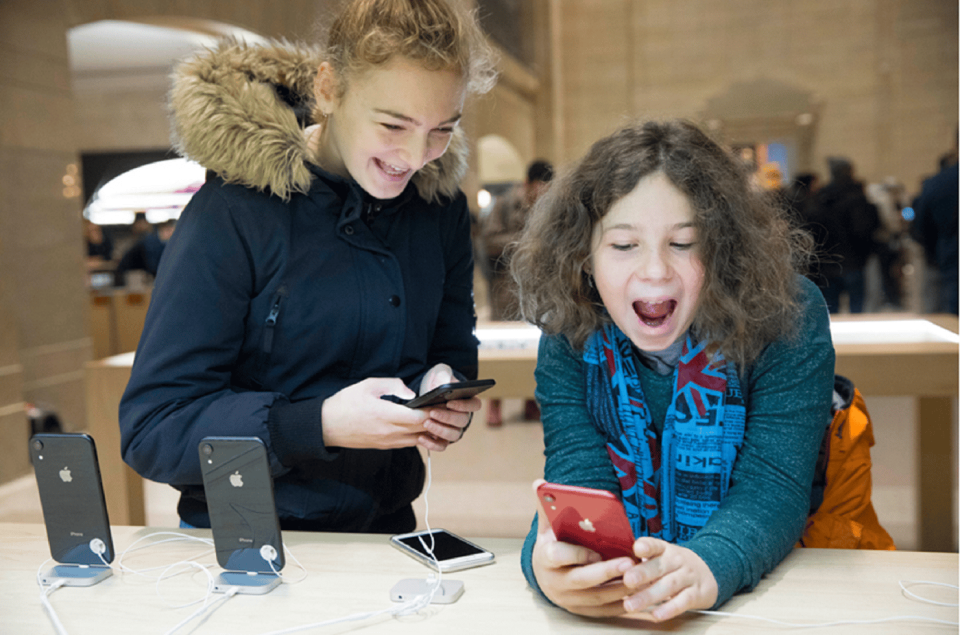 Two exuberant children playing with display iPhones in an Apple Store. 