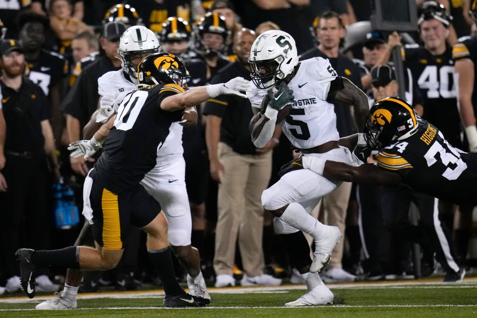 Michigan State running back Nathan Carter runs between Iowa defensive back Quinn Schulte, left, and linebacker Jay Higgins during the first half of MSU's 26-16 loss Saturday, Sept. 30, 2023, in Iowa City, Iowa.