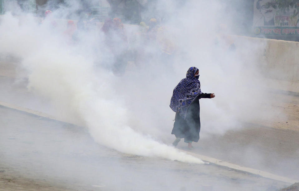 Bangladeshi garment workers run for cover after police fired tear gas to disperse them during a protest in Dhaka, Bangladesh, Wednesday, May 20, 2020. More than 1,000 garment factory workers protested demanding that they be paid their salaries and bonuses ahead of Islam's biggest festival, witnesses and industry officials said. (AP Photo/Sony Ramany)