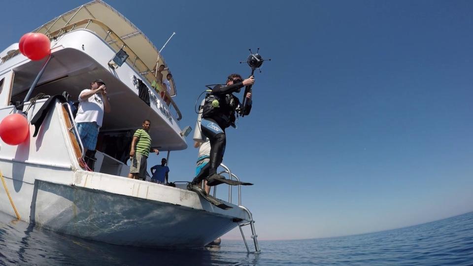 Marine archaeologist Jon Henderson enters the water above the Thistlegorm wreck in the Red Sea with a 360-degree underwater video camera. <cite>Thistlegorm Project</cite>