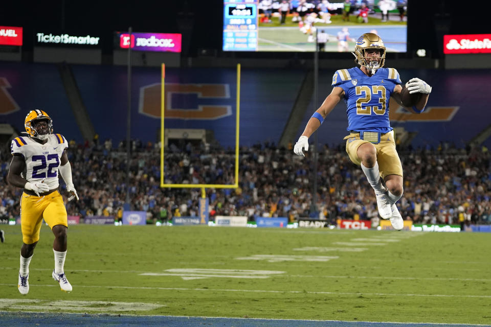 UCLA wide receiver Chase Cota (23) leaps into the end zone for a touchdown after a catch past LSU linebacker Navonteque Strong (22) during the second half of an NCAA college football game Saturday, Sept. 4, 2021, in Pasadena, Calif. (AP Photo/Marcio Jose Sanchez)