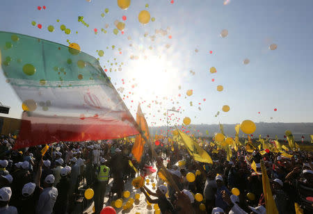 Supporters of Lebanon's Hezbollah leader Sayyed Hassan Nasrallah display Hezbollah and Iranian flags as they listen to him via a screen during a rally marking the 11th anniversary of the end of Hezbollah's 2006 war with Israel, in the southern village of Khiam, Lebanon August 13, 2017. REUTERS/Aziz Taher