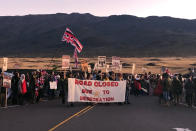 Demonstrators are gather to block a road at the base of Hawaii's tallest mountain, Monday, July 15, 2019, in Mauna Kea, Hawaii, to protest the construction of a giant telescope on land that some Native Hawaiians consider sacred. (AP Photo/Caleb Jones)