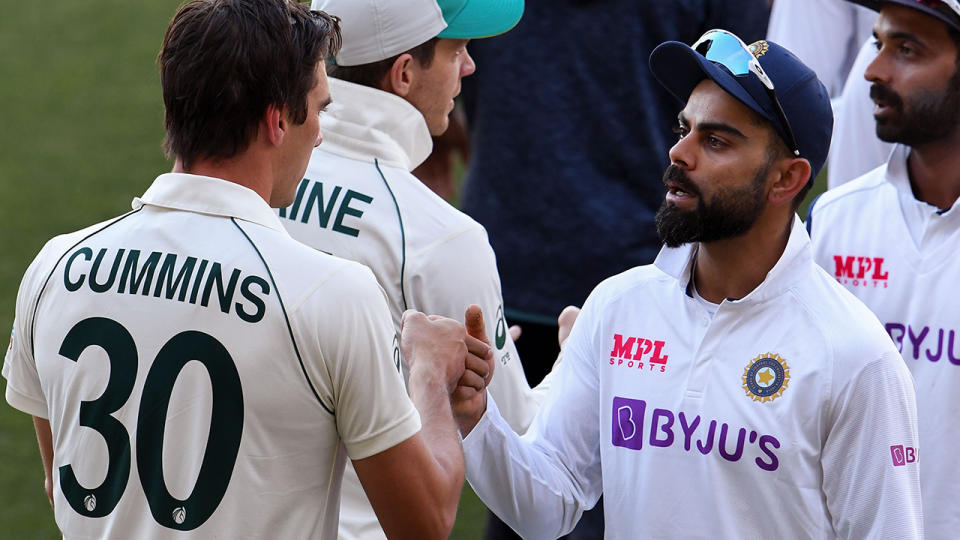 India's Virat Kohli congratulates Australia's Pat Cummins  after Australia's shock victory in the first Test. (Photo by WILLIAM WEST/AFP via Getty Images)