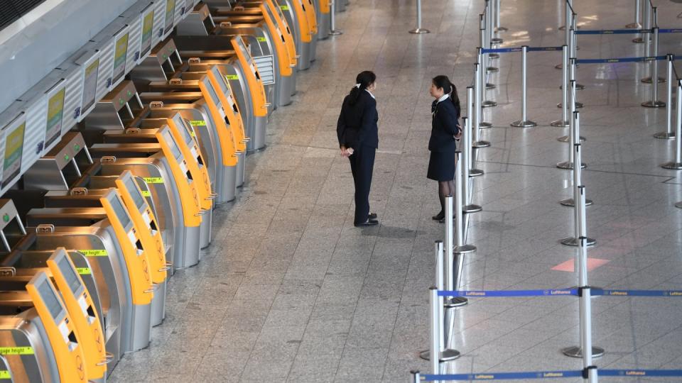 Menschenleer: Lufthansa-Mitarbeiterinnen stehen im Terminal 1 des Frankfurter Flughafens vor verwaisten Check-In-Terminals. Foto: Arne Dedert