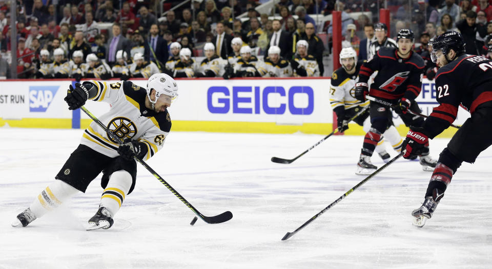 Boston Bruins' Brad Marchand (63) controls the puck against Carolina Hurricanes' Brett Pesce (22) during the first period in Game 3 of the NHL hockey Stanley Cup Eastern Conference final series in Raleigh, N.C., Tuesday, May 14, 2019. (AP Photo/Gerry Broome)