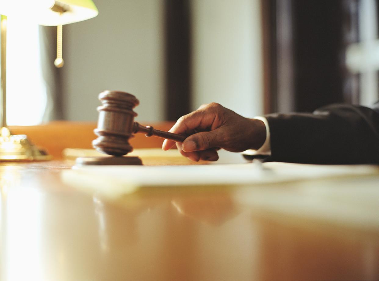 Male judge striking gavel in courtroom, close-up