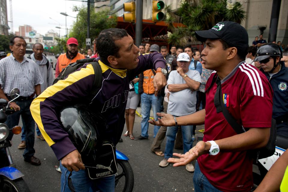 A motor cycle driver, left, argues with demonstrator blocking the highway at Altamira neighborhood in Caracas, Venezuela, Monday, Feb. 24, 2014. Traffic has come to a halt in parts of the Venezuelan capital because of barricades set up by opposition protesters across major thoroughfares. The protests are part of a wave of anti-government demonstrations that have swept Venezuela since Feb. 12 and have resulted in at least 10 deaths. The protests in the capital Monday were peaceful. Police and National Guard troops stood by but did not act to remove the barricades despite the effect on the morning commute. (AP Photo/Rodrigo Abd)