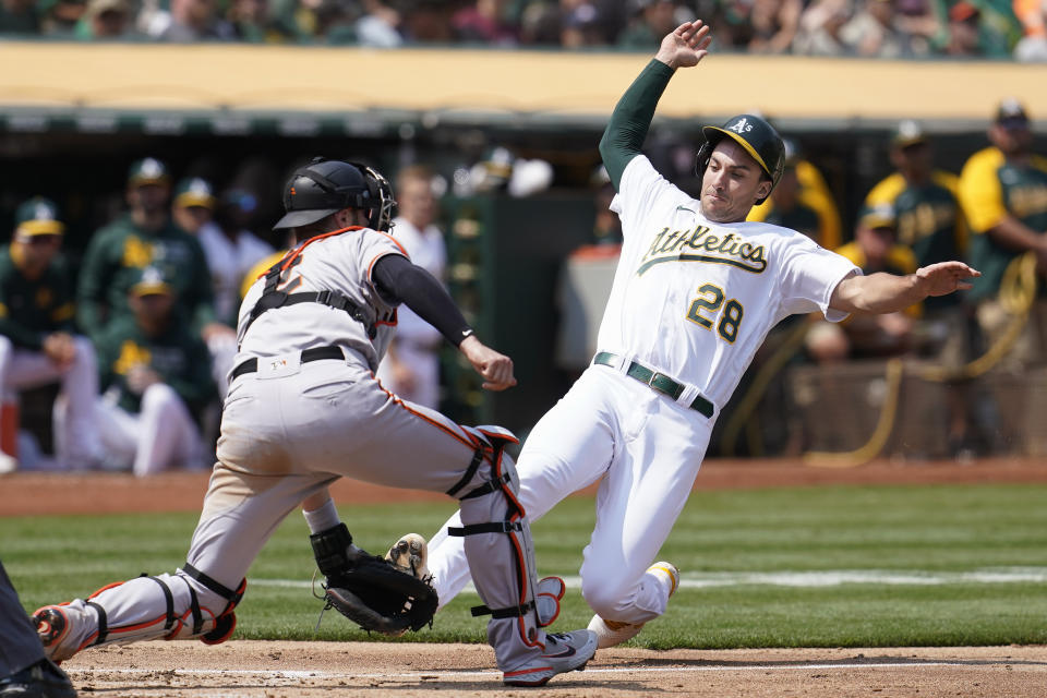 Oakland Athletics' Matt Olson (28) slides home to score against San Francisco Giants catcher Curt Casali during the third inning of a baseball game in Oakland, Calif., Saturday, Aug. 21, 2021. (AP Photo/Jeff Chiu)