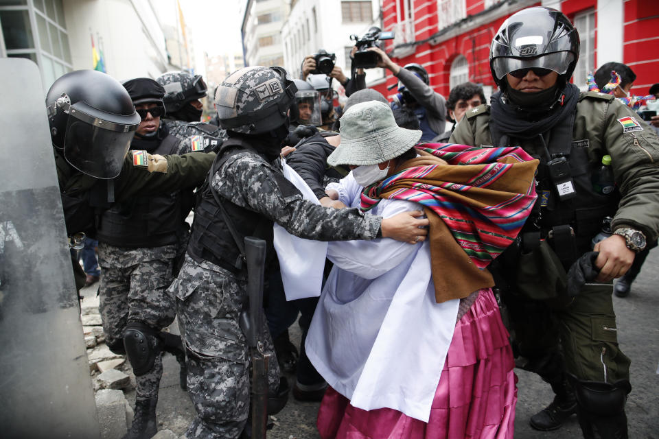 A backer of former President Evo Morales scuffles with police in La Paz, Bolivia, Wednesday, Nov. 13, 2019. The opposition senator who has claimed Bolivia's presidency Jeanine Anez, faces the challenge of stabilizing the nation and organizing national elections within three months at a time of political disputes that pushed Morales to fly off to self-exile in Mexico after 14 years in power. (AP Photo/Natacha Pisarenko)