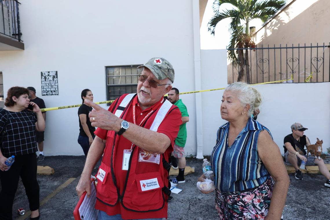 Pete Suarez, left, a volunteer with the Red Cross Disaster Response team, talks to residents while they wait outside for answers after a walkway on the second floor collapsed and the building on Palm Avenue in Hialeah was deemed unsafe on Monday, Oct. 31, 2022.