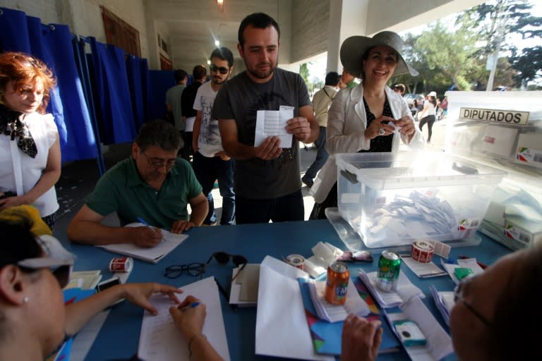 Electoral officers show ballots after closing the polls at the National Stadium in Santiago