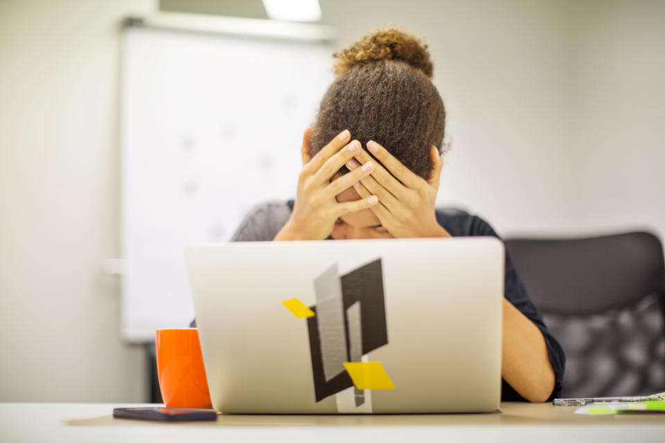 Depressed female professional in panic holding head in hands in front of laptop. Businesswoman frustrated by bad new at office desk.