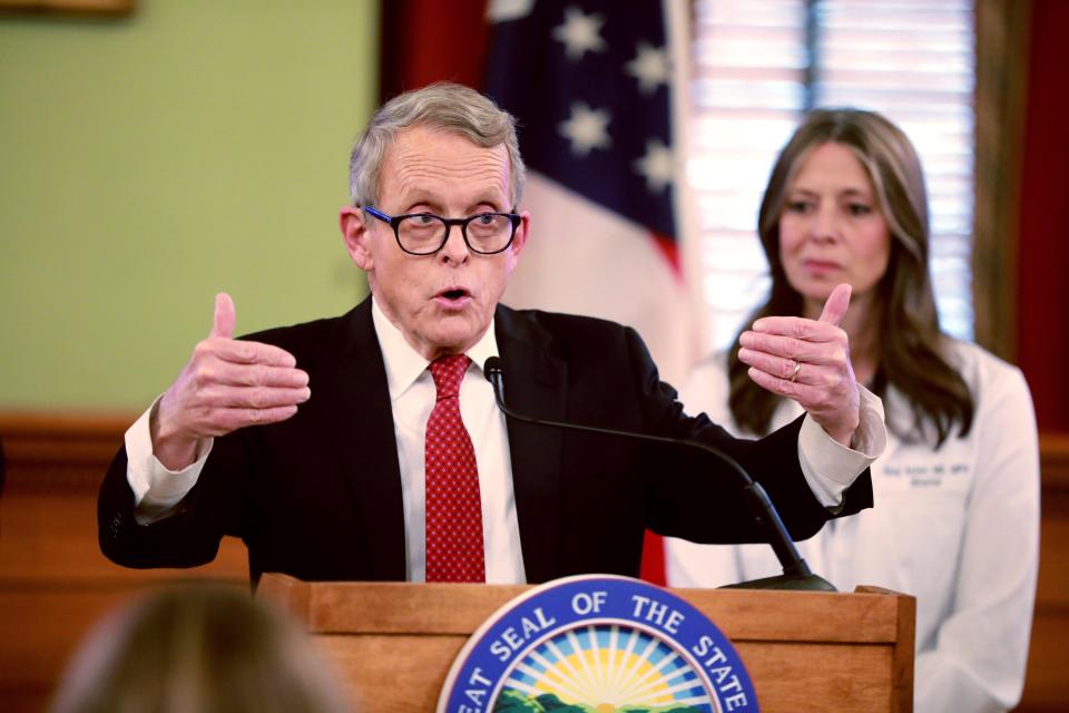 Ohio Gov. Mike DeWine makes a point, as State Health Director Dr. Amy Acton looks on, at a mid-March coronavirus briefing.