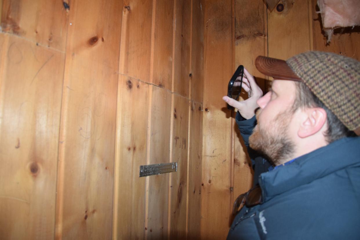 Harbor Springs filmmaker Taylor Dueweke looks at the names on the wall of the Club Ponytail bathroom. He plans to take photos of the names and use them for fundraising, as well as to find people to interview.