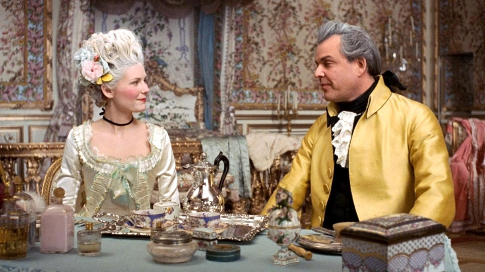 Kirsten Dunst and Danny Huston sit at tea wearing pre-revolution French finery