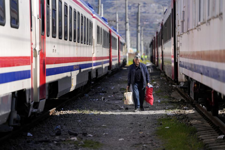 A man walks between trains using as shelters, in Iskenderun city, southern Turkey, Tuesday, Feb. 14, 2023. Thousands left homeless by a massive earthquake that struck Turkey and Syria a week ago packed into crowded tents or lined up in the streets for hot meals as the desperate search for survivors entered what was likely its last hours. (AP Photo/Hussein Malla)