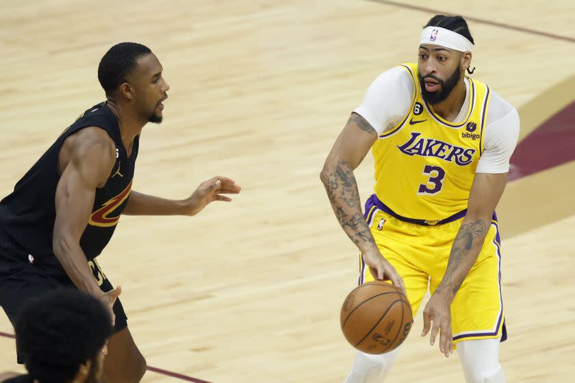 Los Angeles Lakers forward Anthony Davis (3) passes the ball past Cleveland Cavaliers forward Evan Mobley during the first half of an NBA basketball game, Tuesday, Dec. 6, 2022, in Cleveland. (AP Photo/Ron Schwane)