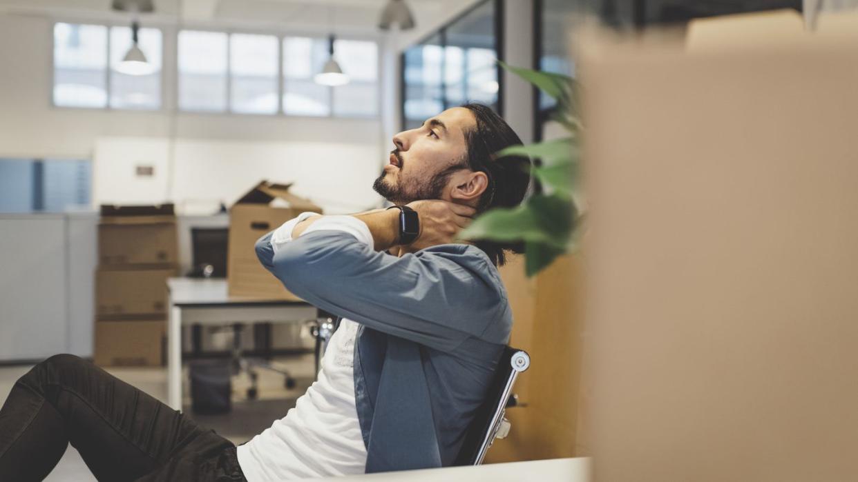 side view of young businessman having neck ache while sitting in new office