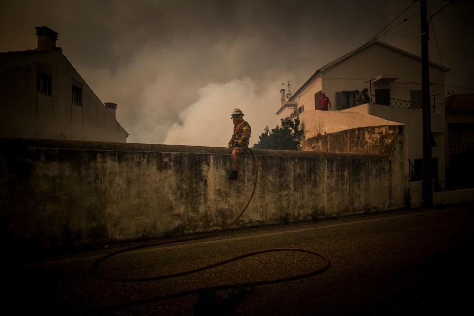 A National Guard Firefighter sits on top of a wall as a wildfire approaches Cardigos village in Macao, central Portugal on July 21, 2019. (Photo: Patricia De Melo Moreira/AFP/Getty Images)