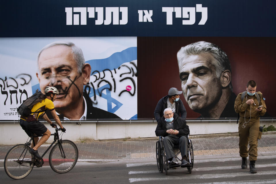 An election campaign billboard for the Likud party that shows a portrait of its leader Prime Minister Benjamin Netanyahu, left, and opposition party leader Yair Lapid, is defaced with Hebrew that reads, "go home," in Ramat Gan, Israel, Sunday, March 21, 2021. Israelis head to the polls on Tuesday for what will be the fourth parliamentary election in just two years. Once again, the race boils down to a referendum on Prime Minister Benjamin Netanyahu. (AP Photo/Oded Balilty)