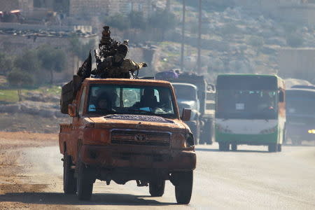 Fighters from a coalition of rebel groups called "Jaish al Fateh", also known as "Army of Fatah" (Conquest Army), escort buses evacuating fighters and civilians from the two besieged Shi'ite towns of al-Foua and Kefraya in the mainly rebel-held northwestern province of Idlib, Syria December 28, 2015. REUTERS/Ammar Abdullah