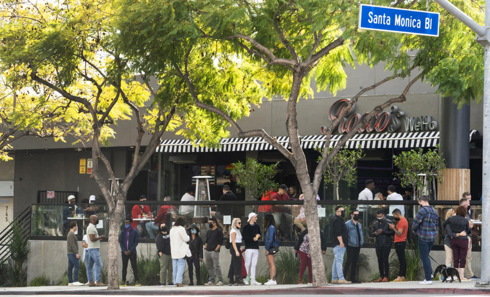 People wait in line for an open terrace table at a restaurant on Valentine's Day during the coronavirus pandemic, Sunday, Feb. 14, 2021, in West Hollywood, Calif. (AP Photo/Damian Dovarganes)